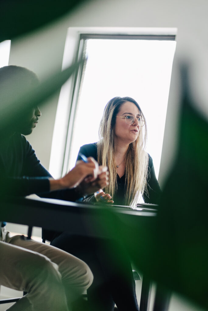 une femme assise à un bureau avec un homme tenant un stylo