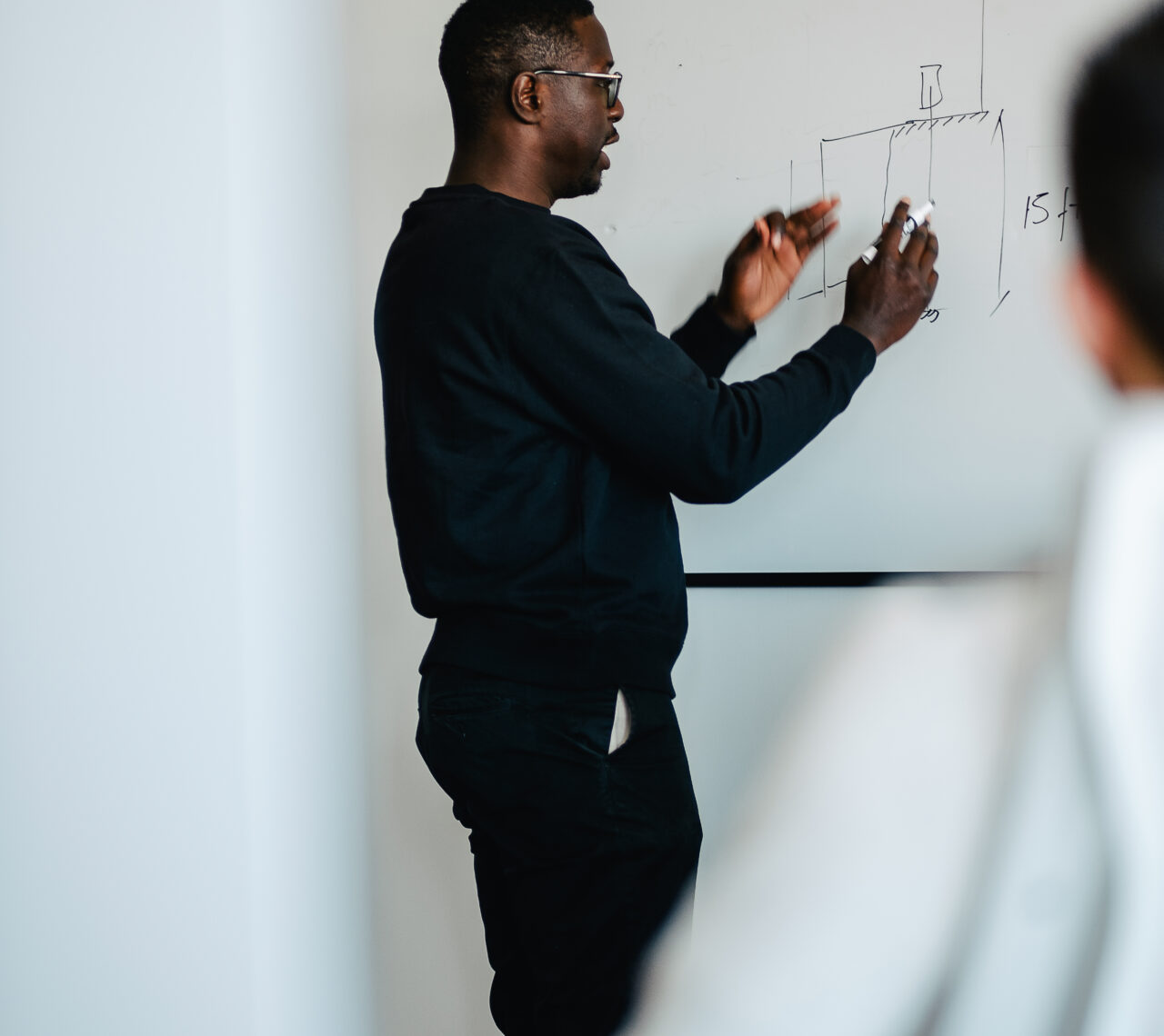 un homme écrivant une structure sur un tableau blanc