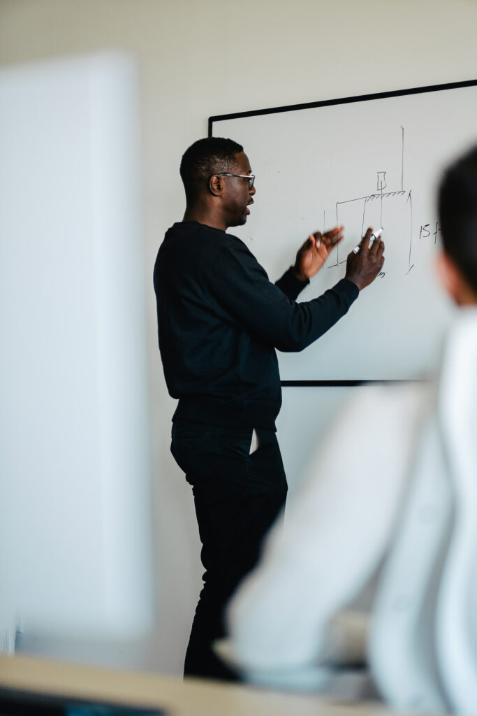 un homme écrivant une structure sur un tableau blanc